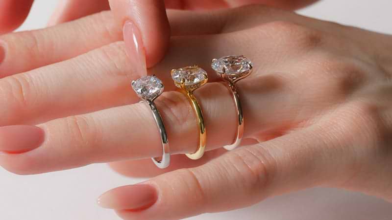 Platinum, yellow gold, and rose gold rings on finger
