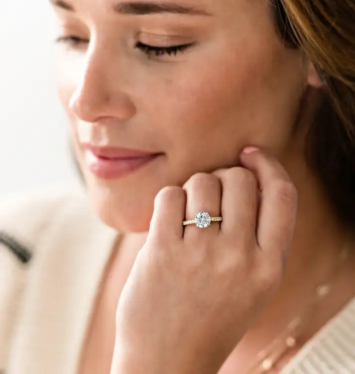 woman with a diamond engagement ring holding her hand up toward her face