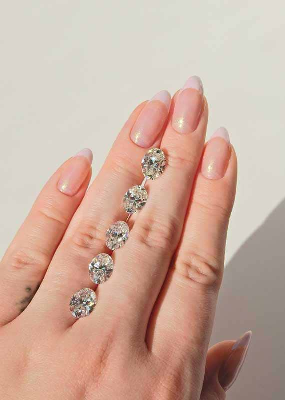 five loose cut oval diamonds on a woman's hand