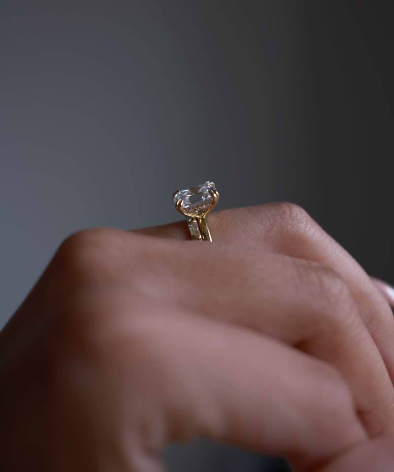 Side view of a yellow gold ring with hidden halo on hand.