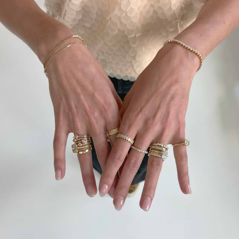 Yellow gold engagement rings and wedding bands stacked on hands.