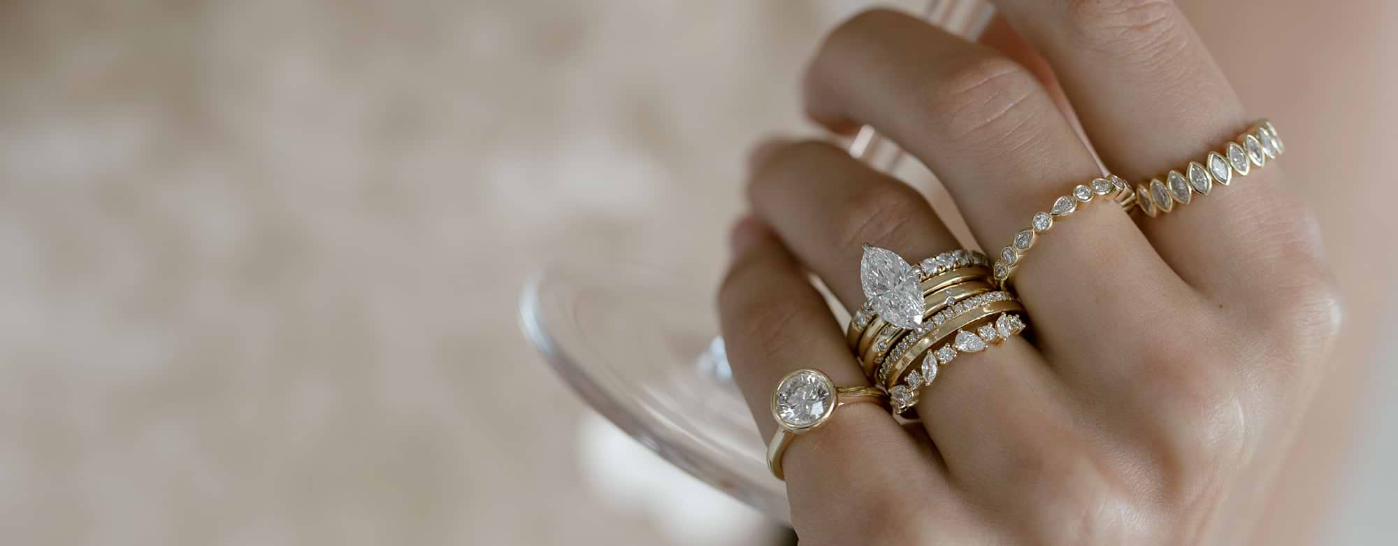 woman's hand with many yellow gold diamond rings in marquise, round, and pear shapes