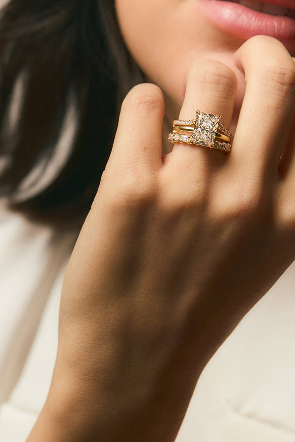 woman wearing diamond engagement ring and yellow gold wedding rings