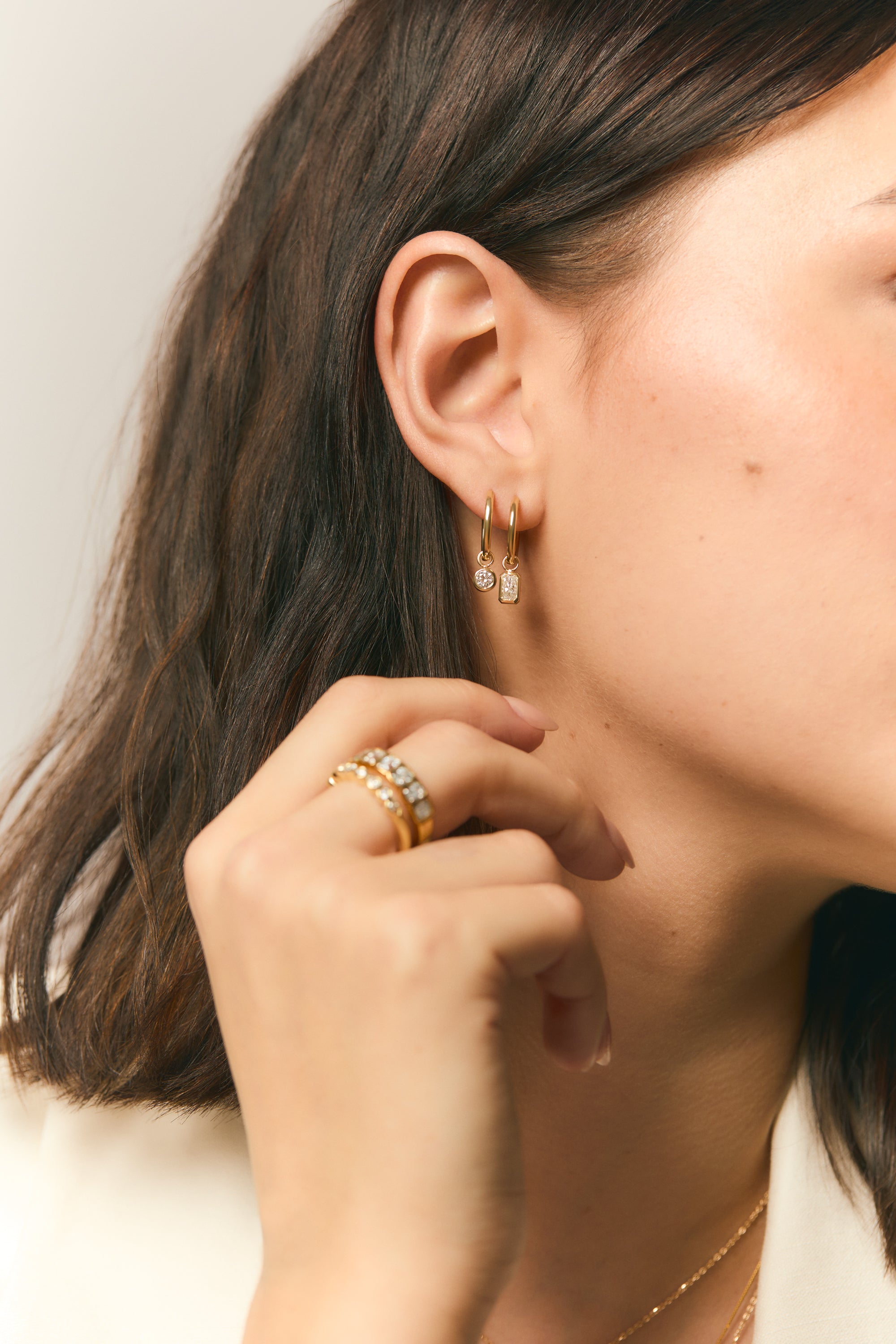 woman holding a hand to her ear wearing yellow gold and diamond fine jewelry