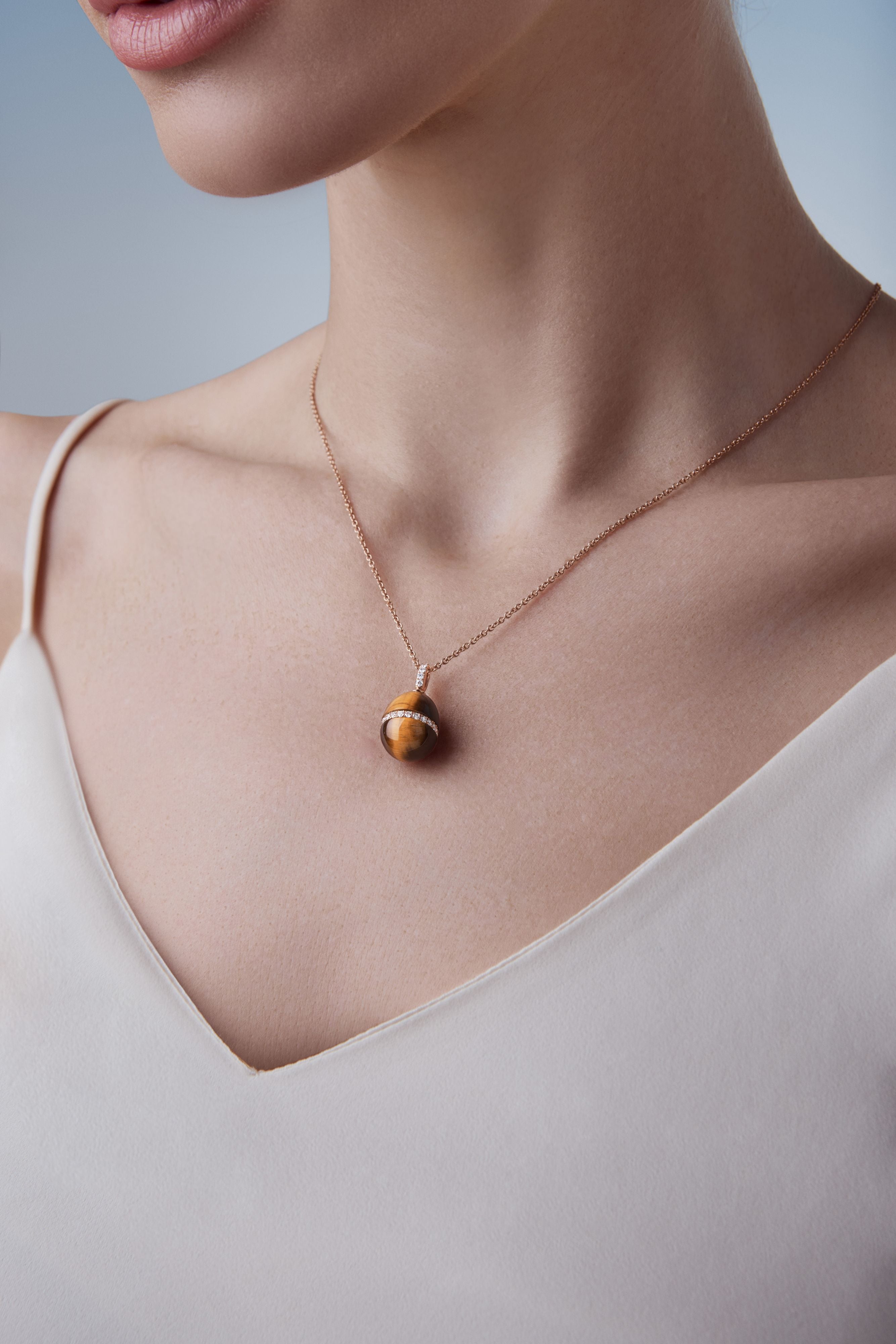 Female model wearing Fabergé Heritage Forever Tigers Eye Pendant in 18k rose gold with diamonds. 