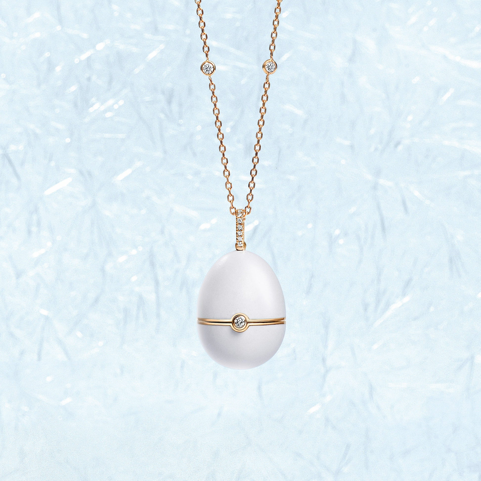 Fabergé white enamel pendant on a patterned light blue background