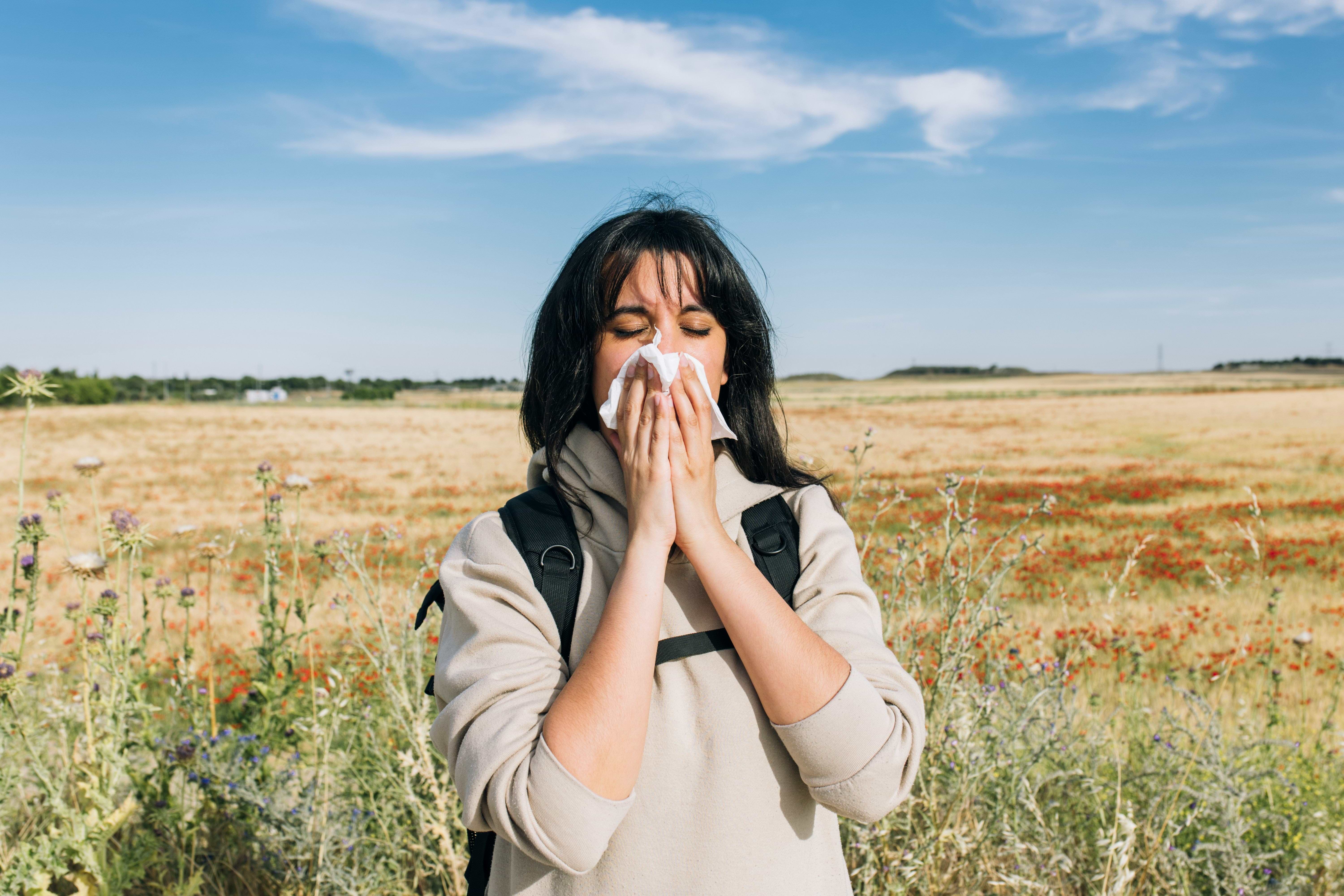 Woman blowing her nose outside in a field.