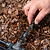 Hand adjusting a black garden irrigation system on mulched ground