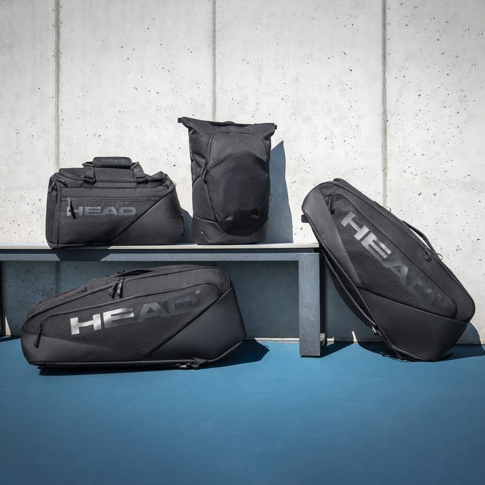 Four black HEAD Pro X 9 Racket Badminton Racket Bags by HEAD are displayed on and in front of a gray bench, set against a concrete wall with a blue floor—ideal for fans of Novak Djokovic’s signature style.
