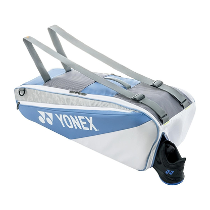 The Yonex 52526EX Club 6 Racket Badminton Bag in Greyish Blue is ideal for badminton fans, featuring shoulder straps and a sporty design with sections of blue, gray, and white. Its versatile pockets accommodate essentials like tennis shoes.