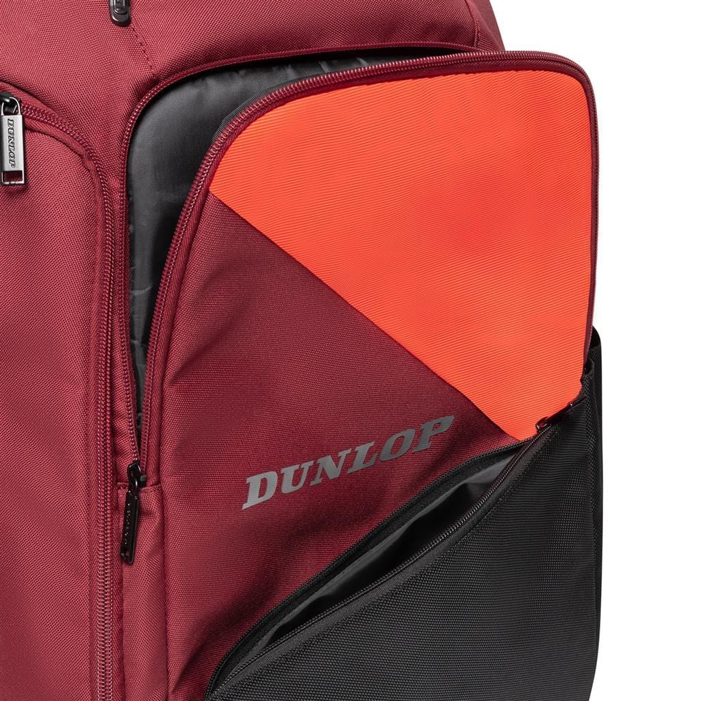 The Dunlop CX Performance Badminton Backpack in black and red showcases a partially open front pocket that reveals an orange interior. This pocket includes a black section at the bottom, with "Dunlop" printed in gray on the front. It's perfect for storing gear such as the Dunlop CX Performance rackets holder.