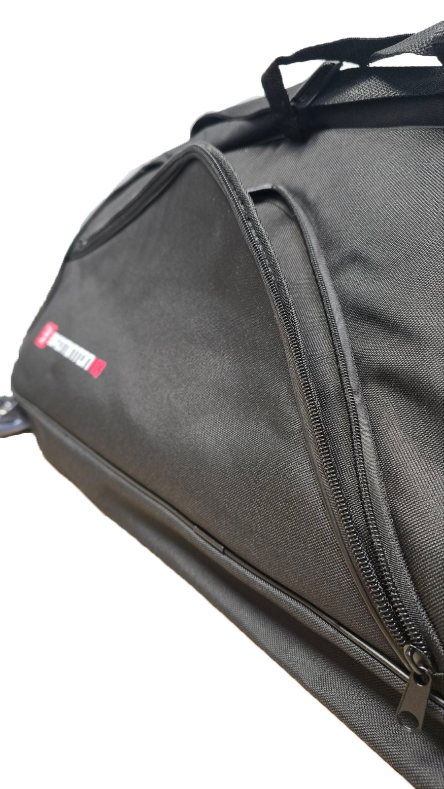 A close-up of the BadmintonHQ 6 Racket Badminton Bag in black shows a partially open zipper revealing a side pocket. The sturdy fabric features a small red and white label, highlighting the trusted BadmintonHQ brand.