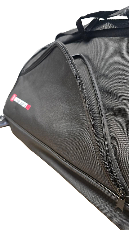 A close-up of the BadmintonHQ 6 Racket Badminton Bag in black shows a partially open zipper revealing a side pocket. The sturdy fabric features a small red and white label, highlighting the trusted BadmintonHQ brand.