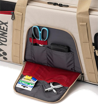 A close-up of an open side pocket on the Yonex BA72631WEX Gearlogic Tournament Badminton Bag in beige, displaying neatly organized compartments with scissors, a wallet, cards, a USB cable, and other small items inside.