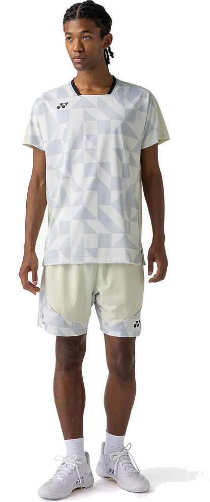 A person stands facing forward wearing a light gray geometric-patterned athletic shirt and Yonex 15240YX Knit Mens Badminton Shorts in Champagne, paired with white socks and sneakers, on a white background.