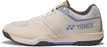 The Yonex Strider Flow WIDE Men's Badminton Shoes in Light Beige feature light blue accents, a Yonex logo, Power Cushion branding, mesh upper, lace-up design, and a durable dark rubber sole—ideal for beginners.