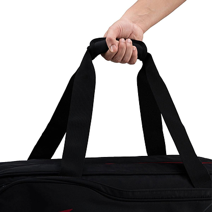 A hand holds the handles of the Li-Ning Team 6 Racket Badminton Bag - Black by Li-Ning, shown against a plain white background.