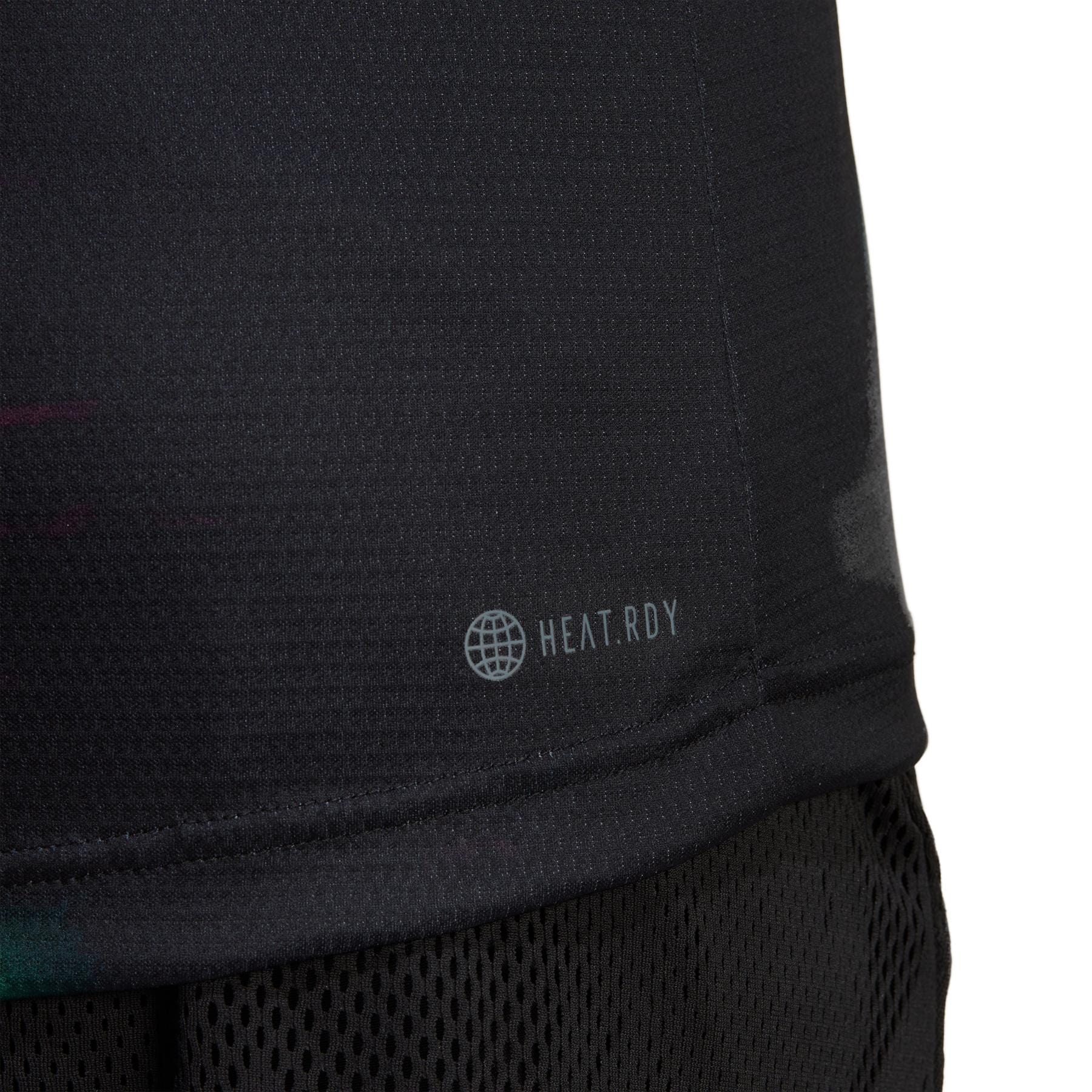 Close-up of an eco-friendly black athletic shirt, labeled with "HEAT.RDY" and a globe icon, crafted using sustainable carbon recycling. The adidas Melbourne Men's Freelift Polo Shirt features a textured, breathable design, perfectly paired with black mesh shorts.