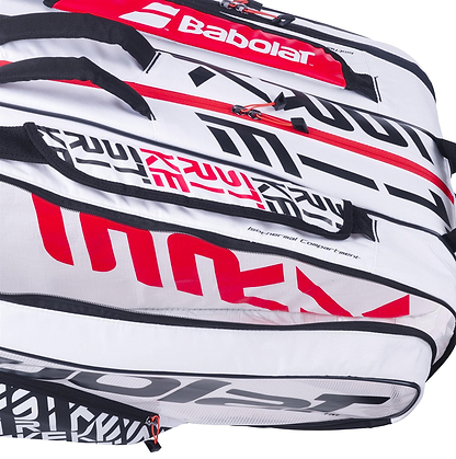 Close-up of the Babolat RH12 Pure Strike 12 Racket Bag in white, black, and red. The bag features bold modern lettering and a variety of compartments, including a Clear View Shoe Compartment, offering ample storage for tennis gear.
