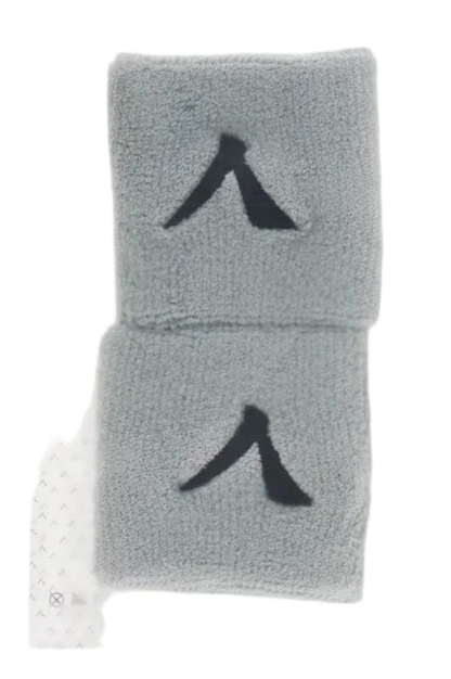 A sealed package contains a pair of gray wristbands designed for maximum comfort, each with a black abstract logo. The clear packaging has a white top label that reads "Kanso 7cm Wristband - 2 Pack - Grey" against a plain white background.