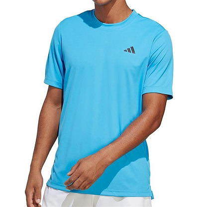 A person wearing a Pulse Blue ADIDAS Men's Club Badminton T-Shirt, featuring AEROREADY technology and a small black adidas logo on the chest. The individual stands with one hand near their waist against a plain white background, embodying sporty elegance and readiness for action.