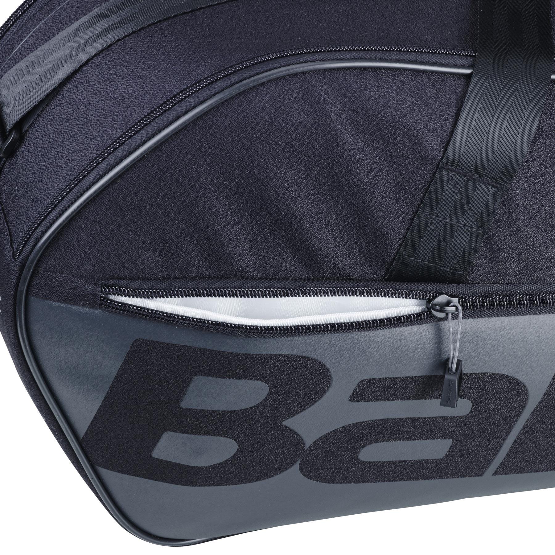 Close-up of the Babolat Court M 6 Racket Badminton Bag in black, showcasing a zippered pocket and bold lettering. Made from recycled PET, the durable fabric and prominent zip pull emphasize its sleek design.