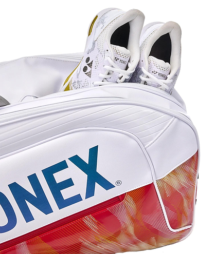 A close-up of the Yonex 02626EX Expert 6 Racket Badminton Bag in white, partially unzipped to show white Yonex athletic shoes inside, emphasizing its Thermo Guard feature and signature red and yellow pattern.