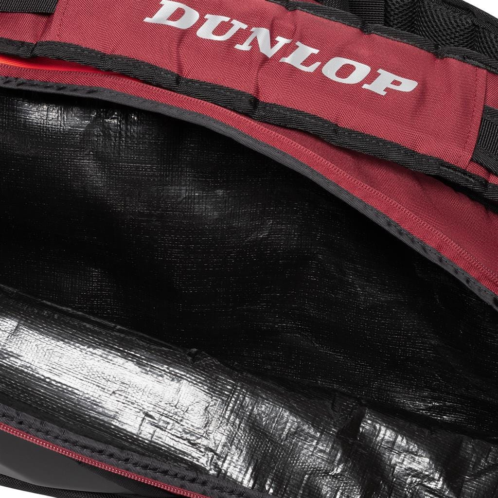 Close-up image of an open Dunlop CX Performance 12 Badminton Racket Bag in black and red, featuring a prominent "Dunlop" logo on the top. The interior is empty, showcasing a shiny black lining designed for optimal racket storage.