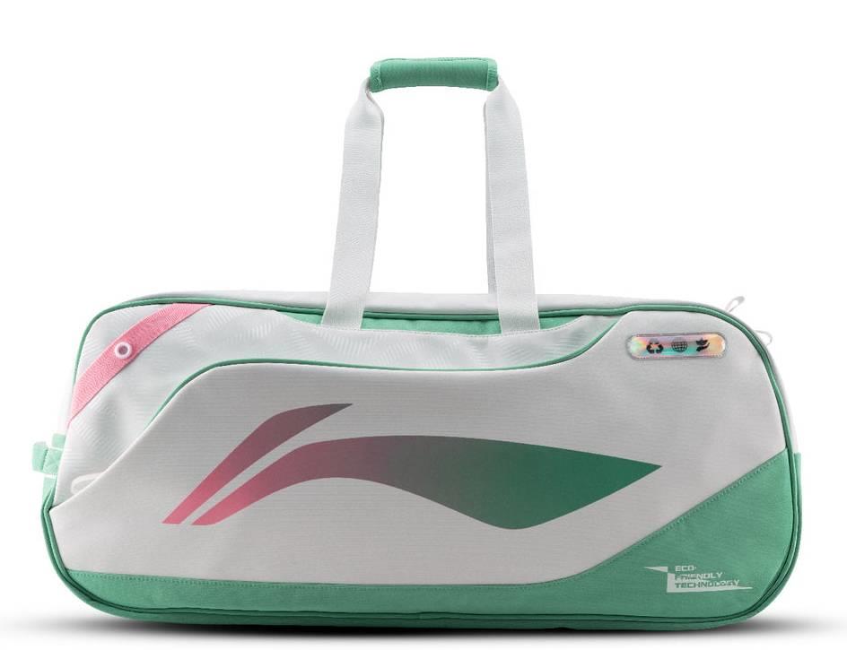 The Li-Ning Competition 6 Racket Badminton Bag in white and green features pink accents, a modern abstract design, sturdy handles, a zipper closure, and a small multicolored tag near the top right corner.