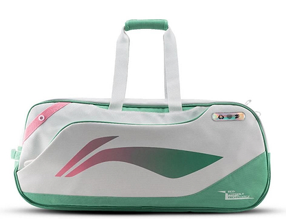 The Li-Ning Competition 6 Racket Badminton Bag in white and green features pink accents, a modern abstract design, sturdy handles, a zipper closure, and a small multicolored tag near the top right corner.