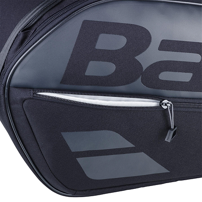Close-up of the Babolat Court L 9 Racket Badminton Bag in black, showcasing a bold "B" on the main compartment. It features a zippered front pocket with visible zipper and pull tab, made from durable textured fabric ideal for eco-friendly sports enthusiasts.
