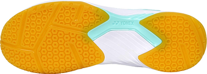 Close-up of the Yonex Power Cushion SHB 101 Badminton Shoes sole, showing a textured yellow and orange grip, mint midfoot, and white upper. The design highlights Yonex's shock-absorption technology for enhanced badminton performance.