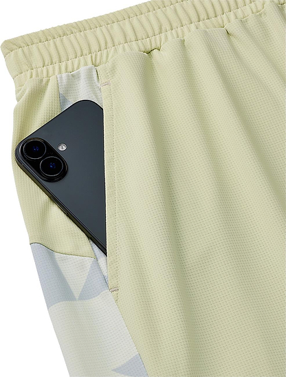 A black smartphone is partially tucked into the side pocket of Yonex 15240YX Knit Mens Badminton Shorts - Champagne, featuring an elastic waistband.