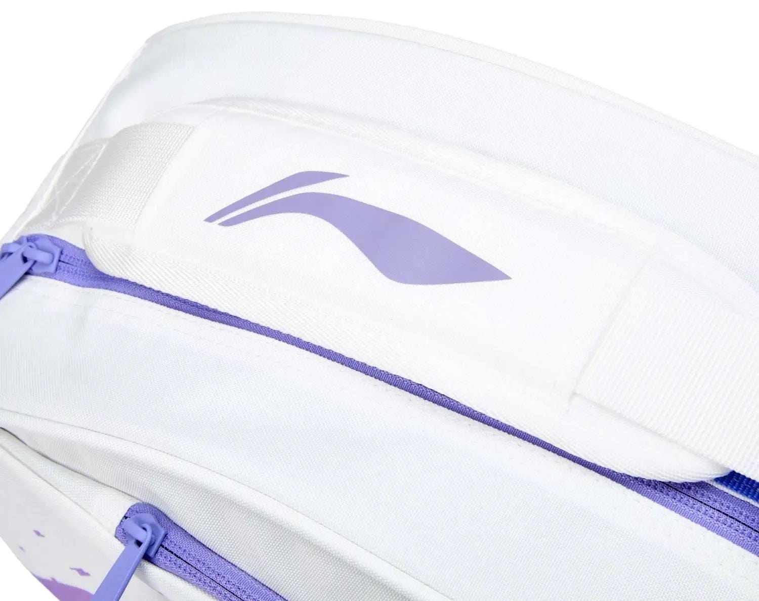 Close-up of the Li-Ning Training Series 3 Racket Badminton Bag in white with a purple zipper and abstract logo on the padded strap. The sleek fabric, branded details, and stylish purple accents keep your badminton gear organized.