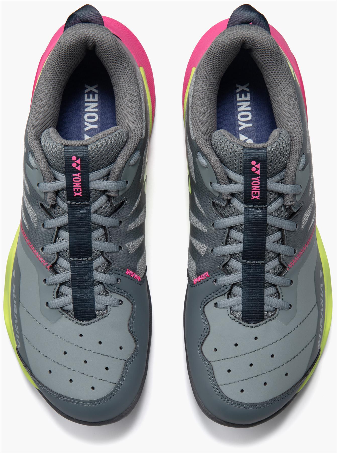 A pair of Yonex Subaxia GT WIDE Unisex Badminton Shoes in grey, with dark blue laces, pink accents, neon yellow soles, and GRPHT THRTTL technology, viewed from above on a plain white background.