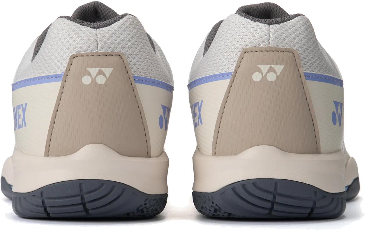 A close-up rear view of two light beige Yonex Strider Flow WIDE Men's Badminton Shoes with textured soles and Yonex logos on the heels—perfect for beginner players.
