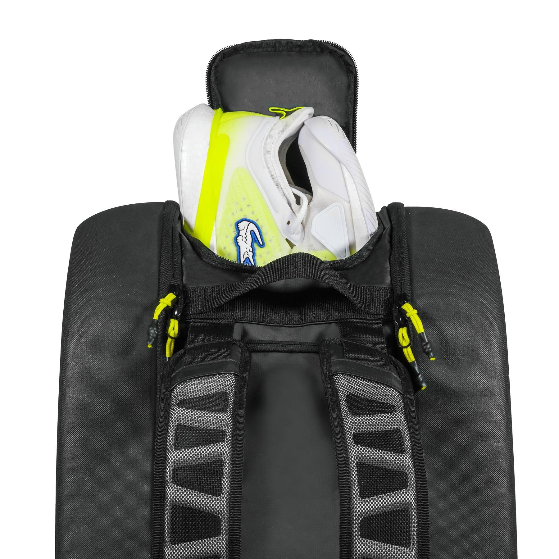A pair of white sneakers with yellow accents and lightweight EVA soles are partially packed inside a Tecnifibre Reform L Badminton Racket Bag - Black, featuring gray straps and yellow zipper pulls by Tecnifibre.