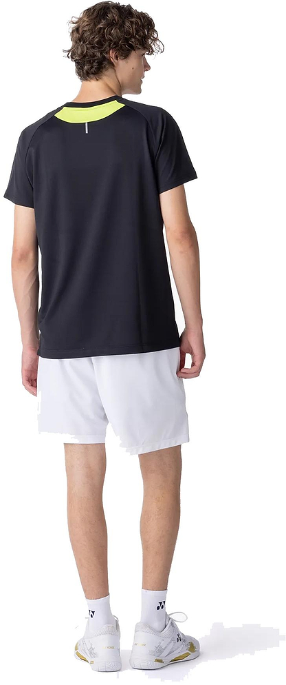 A young man with curly hair faces away, wearing the Yonex 10711YX Crew Neck Men's Badminton T-Shirt in black by Yonex, paired with white athletic shorts, socks, and sneakers against a plain white background.