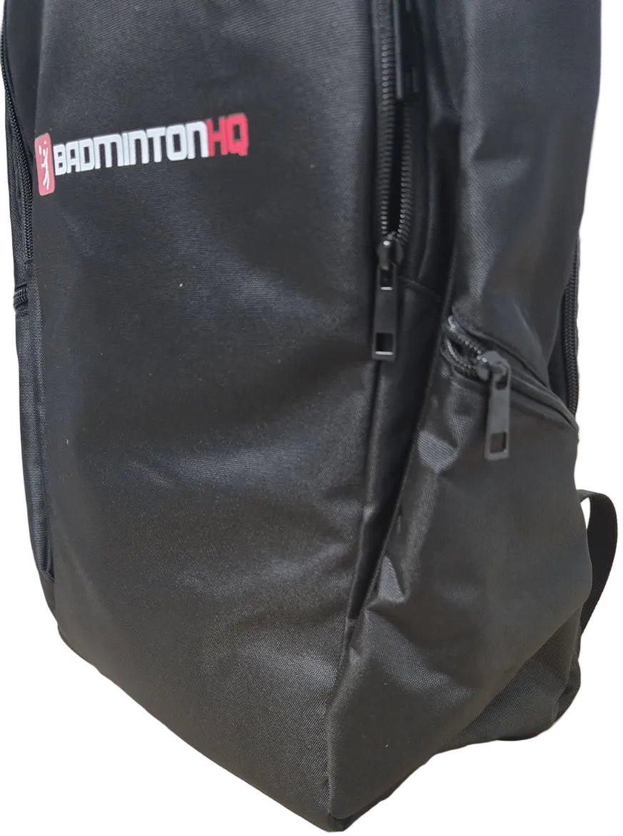 The BadmintonHQ Badminton Backpack - Black features multiple zippered pockets, a visible side pocket, and the "BADMINTONHQ" logo in white and red—ideal as a stylish badminton kit bag.
