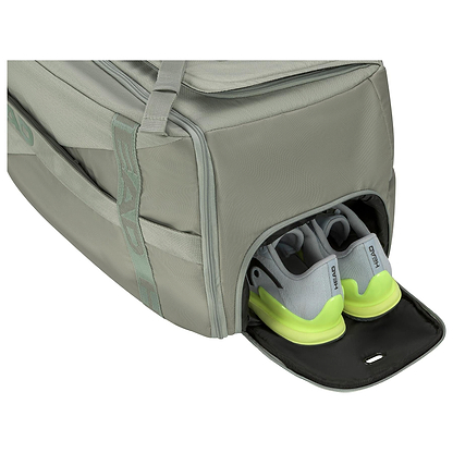 A HEAD Pro Badminton Duffle Bag L LNLL in gray is displayed with its side compartment partially open, showcasing a pair of gray and neon green athletic shoes. The main compartment is zipped shut, ensuring that everything remains securely stored within its spacious interior.
