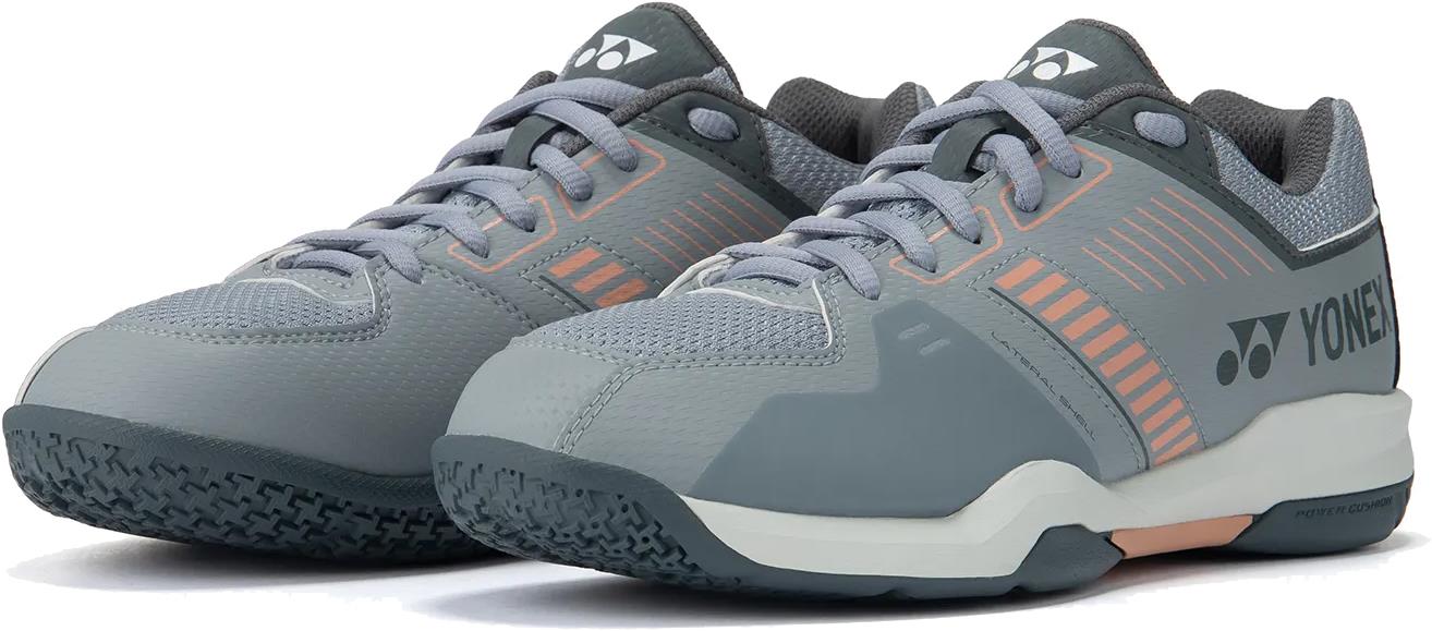 Yonex Strider Flow Unisex Badminton Shoes in light grey with peach and white accents, featuring textured rubber soles and laces, displayed on a white background.