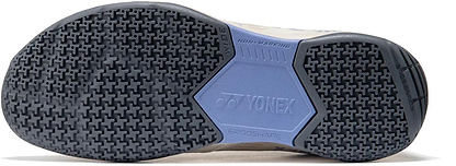 The image shows the sole of Yonex Strider Flow WIDE Mens Badminton Shoes in light beige, with a textured black and blue non-marking grip, "ERGOSHAPE," and the Yonex logo embossed in the center—ideal for beginner players.