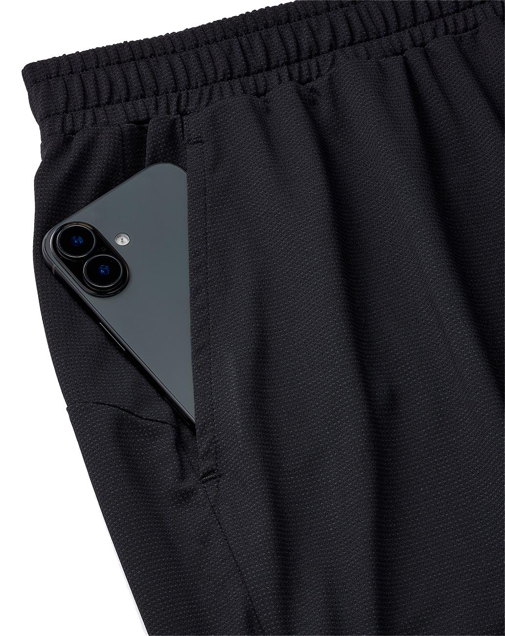 A Yonex 15239YX Knit Men's Badminton Short in black with an elastic waistband, pictured with a smartphone partially tucked into the pocket—ideal for combining style and function on the court.