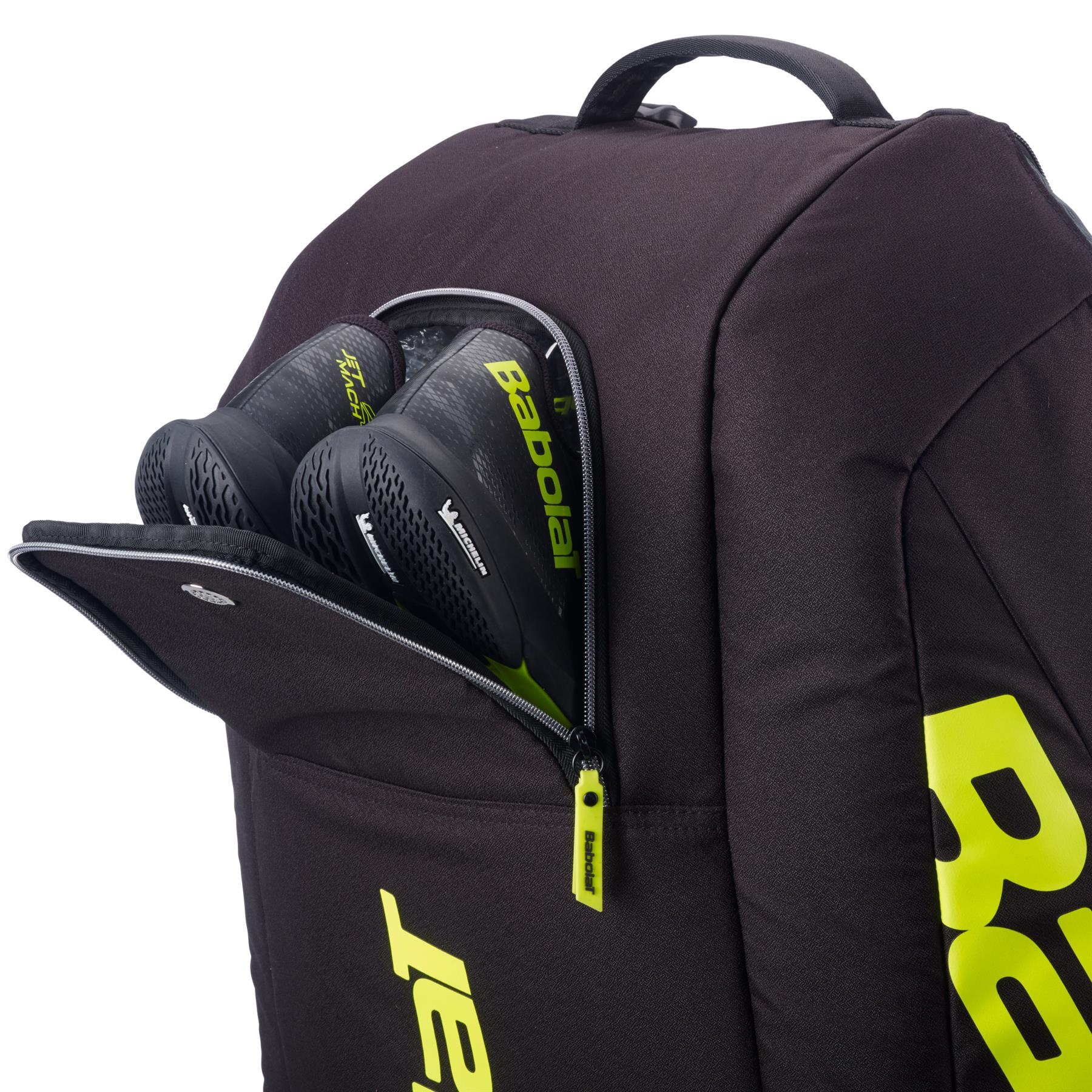 A grey and yellow Babolat RH12 Pure Aero 12 Racket Badminton Bag is shown unzipped, revealing a pair of black Babolat shoes inside.