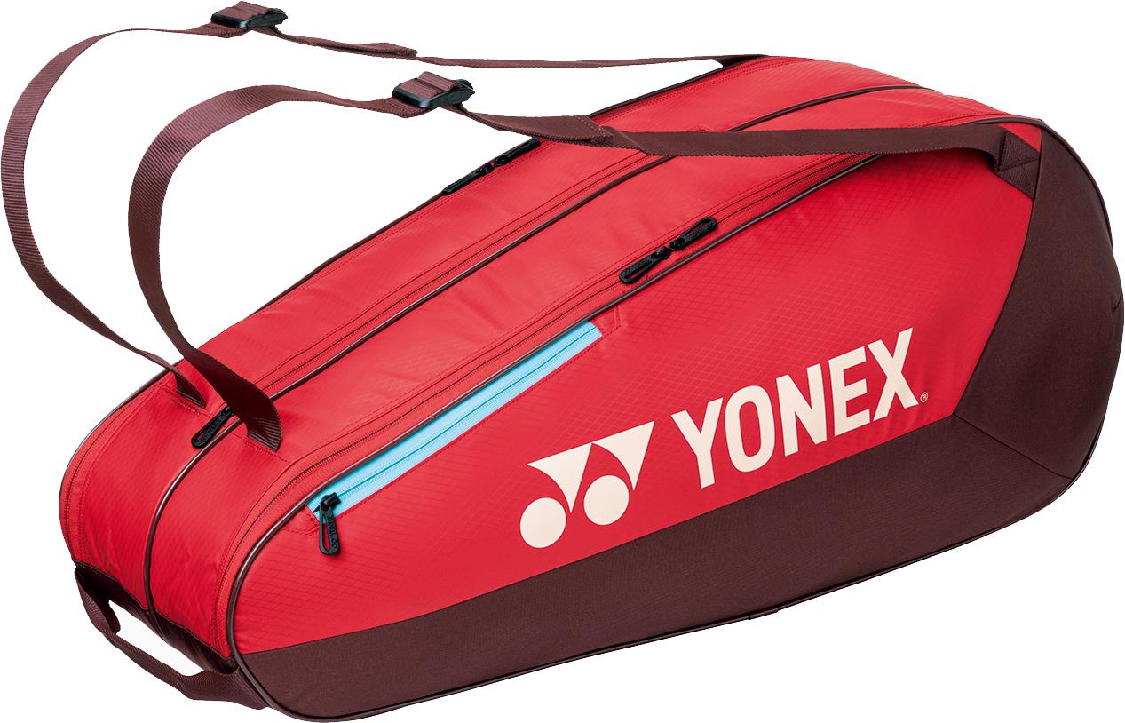 The Yonex 42526EX Team 6 Racket Badminton Bag in ruby red features a large white Yonex logo, multiple zippered compartments, and adjustable shoulder straps—perfect for stylishly carrying your badminton gear.