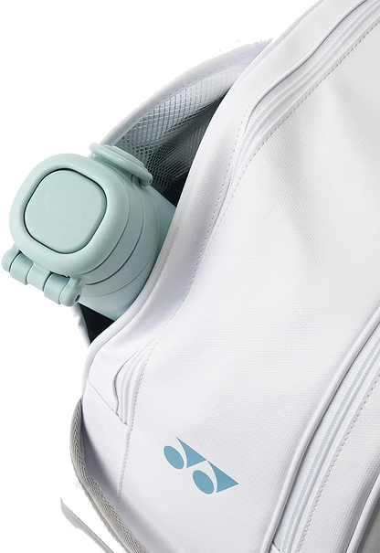 A light blue collapsible water bottle is partially visible inside the open pocket of a white Yonex 02631WEX Expert Tournament Badminton Bag, which features a blue Yonex logo on the front.