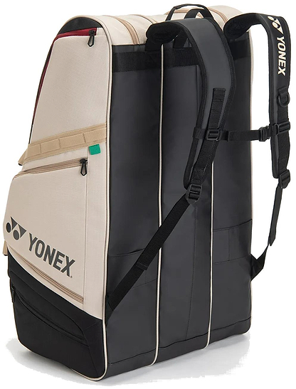 The Yonex BA726212EX Gearlogic 12 Racket Badminton Bag in beige features backpack straps, a side pocket, tan-black design, and Yonex logos; it holds up to 12 rackets plus gear for spacious storage.