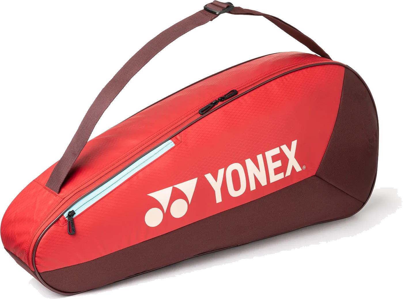 The Yonex 42523EX Team 3 Racket Badminton Bag in Ruby Red is a lightweight, red and brown bag with a shoulder strap, zipper, and white Yonex logo, designed to hold up to 3 rackets for convenient on-the-go use.