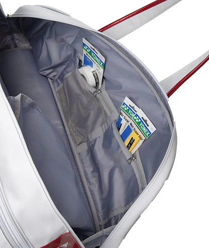 The Yonex 02631WEX Expert Tournament Badminton Bag in white features silver-grey lining, red shoulder straps, and an inner zipper mesh pocket storing two Yonex grip tapes and a roll of white grip tape—ideal for tournaments.