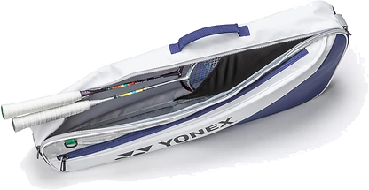 The Yonex BA52523EX Club 3 Racket Badminton Bag in white and blue is shown unzipped, revealing two racquets with white grip handles inside. This lightweight Yonex bag features a side logo and a convenient carrying handle.